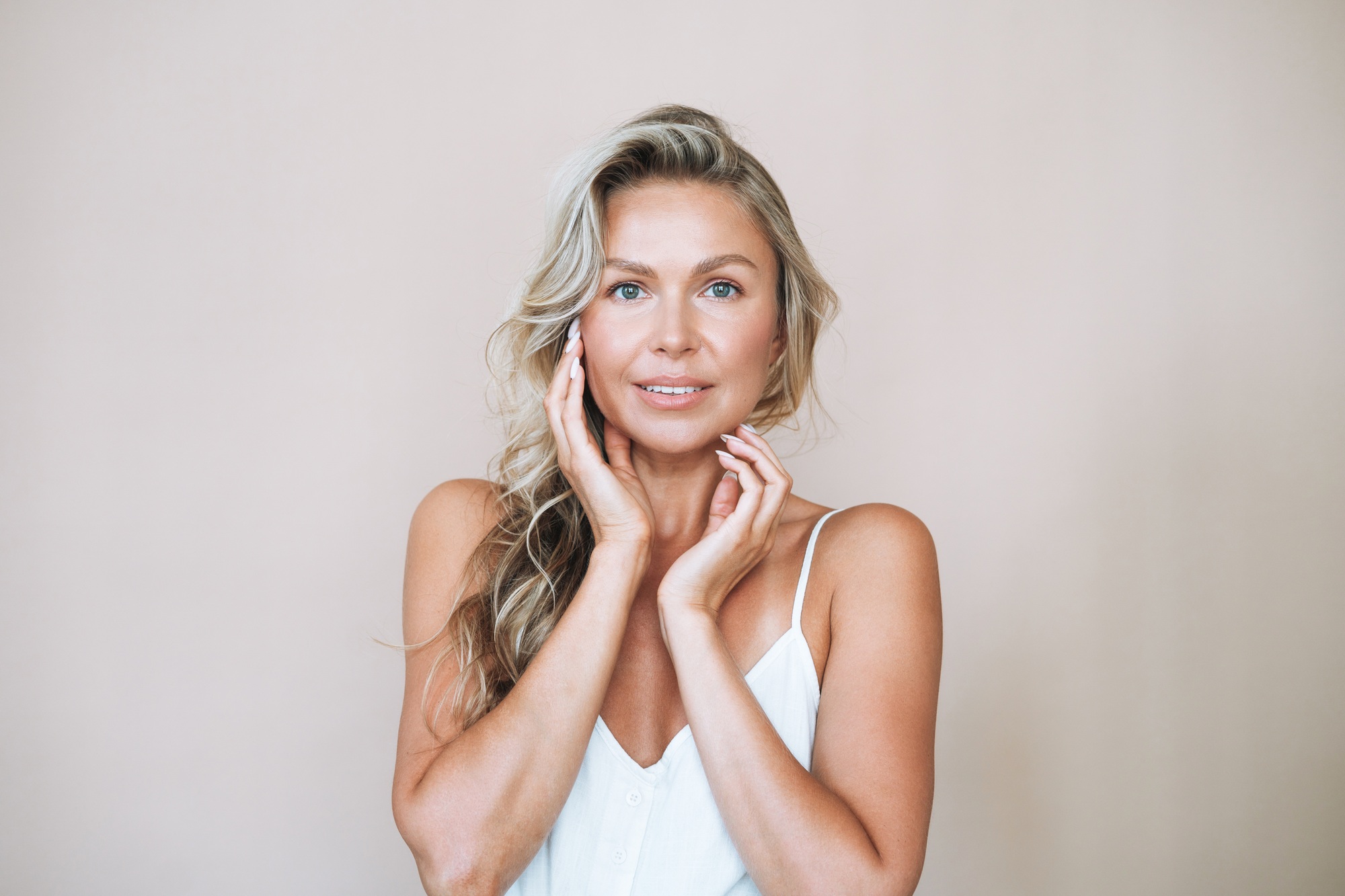 Beauty portrait of blonde hair smiling young woman isolated on beige background